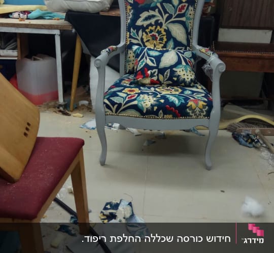 כיסא מרופד בבד פרחוני צבעוני על רצפה מבולגנת